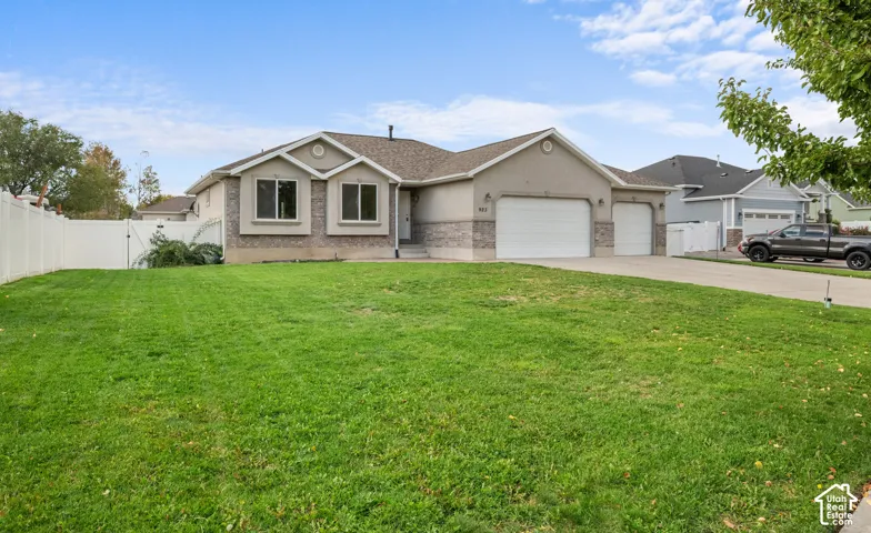 Two-car garage, single-car garage, concrete driveway, stone exterior accents, and a white privacy fence