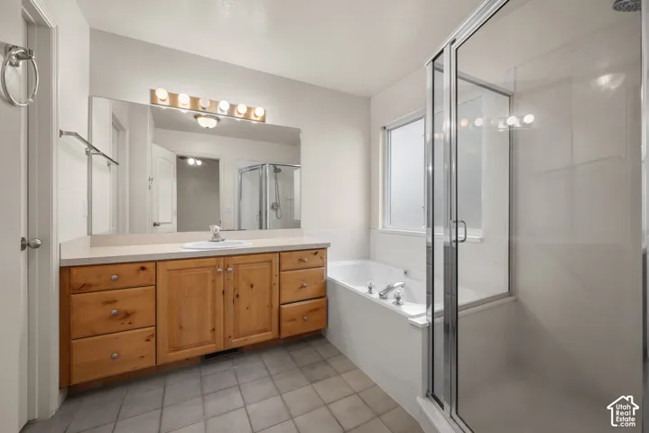 Expansive vanity with wood cabinetry and an integrated sink, large mirror, and full light fixture