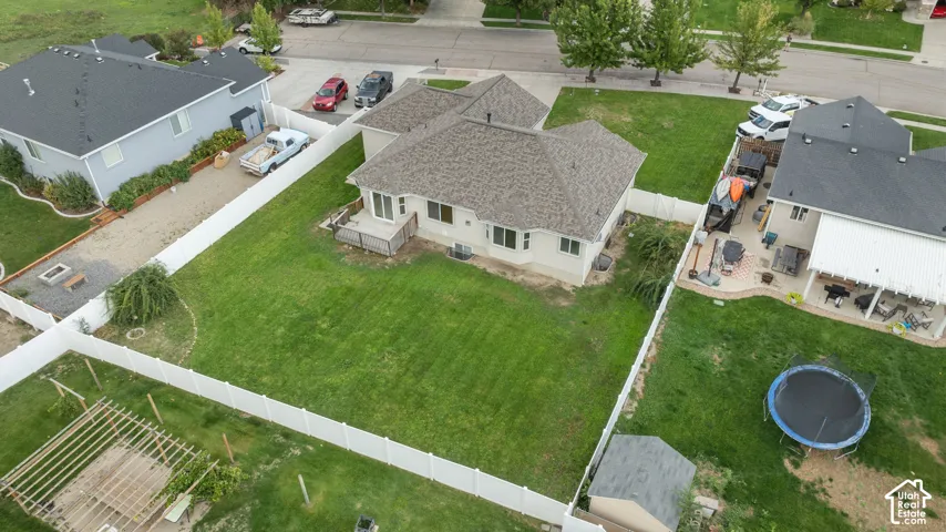 Expansive backyard featuring a manicured lawn, a white privacy fence, and a gravel side yard with a fire pit