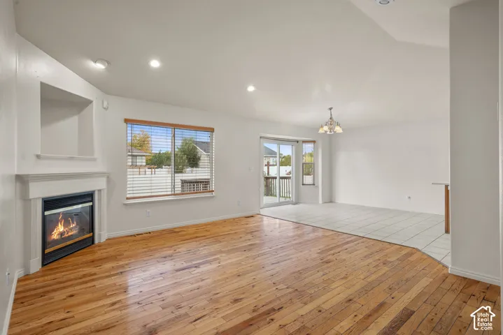 Hardwood flooring, built-in fireplace with mantel, recessed lighting, sliding glass door, and tiled flooring