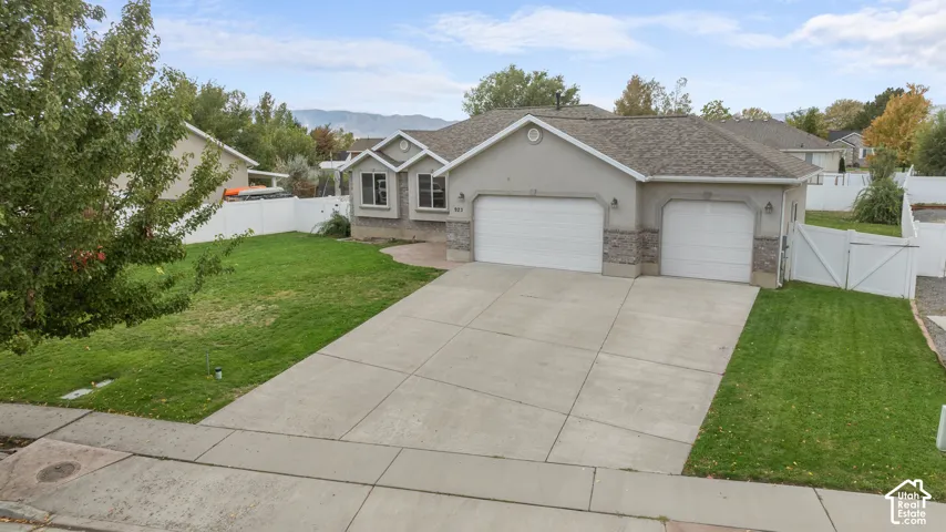 Stucco exterior with stone accents, dual garage doors, and a concrete driveway