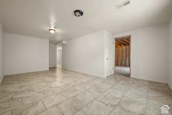 Spacious room featuring tile flooring, white painted walls, and recessed lighting fixtures