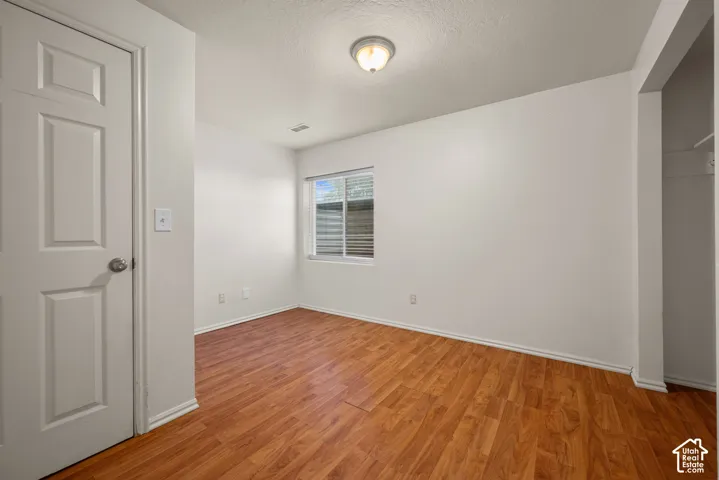 Wood-finish flooring, white paneled door, window with blinds, overhead flush mount light fixture