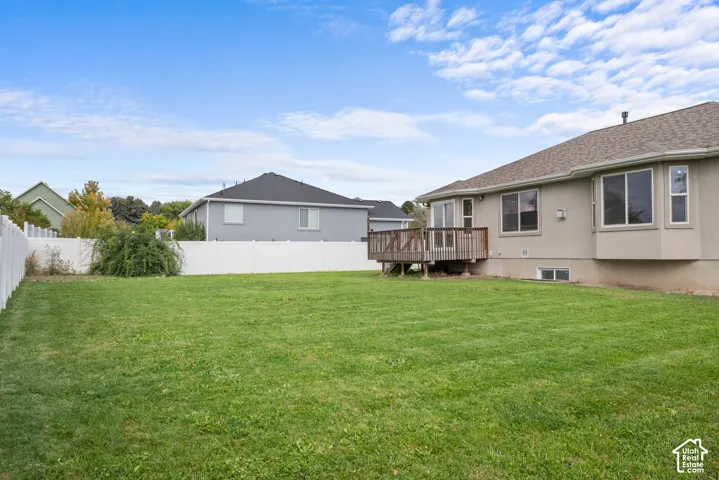 Expansive green lawn with a white privacy fence