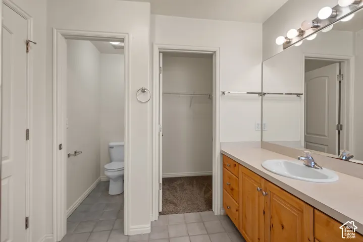 Bathroom featuring an extended single vanity with an integrated sink, wood-finish cabinetry, and a large wall-mounted mirror