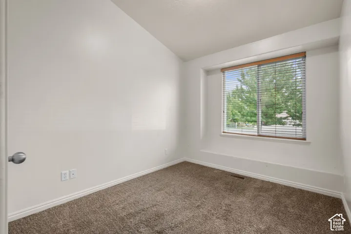 Neutral wall finishes, textured carpeting, and a window with horizontal blinds