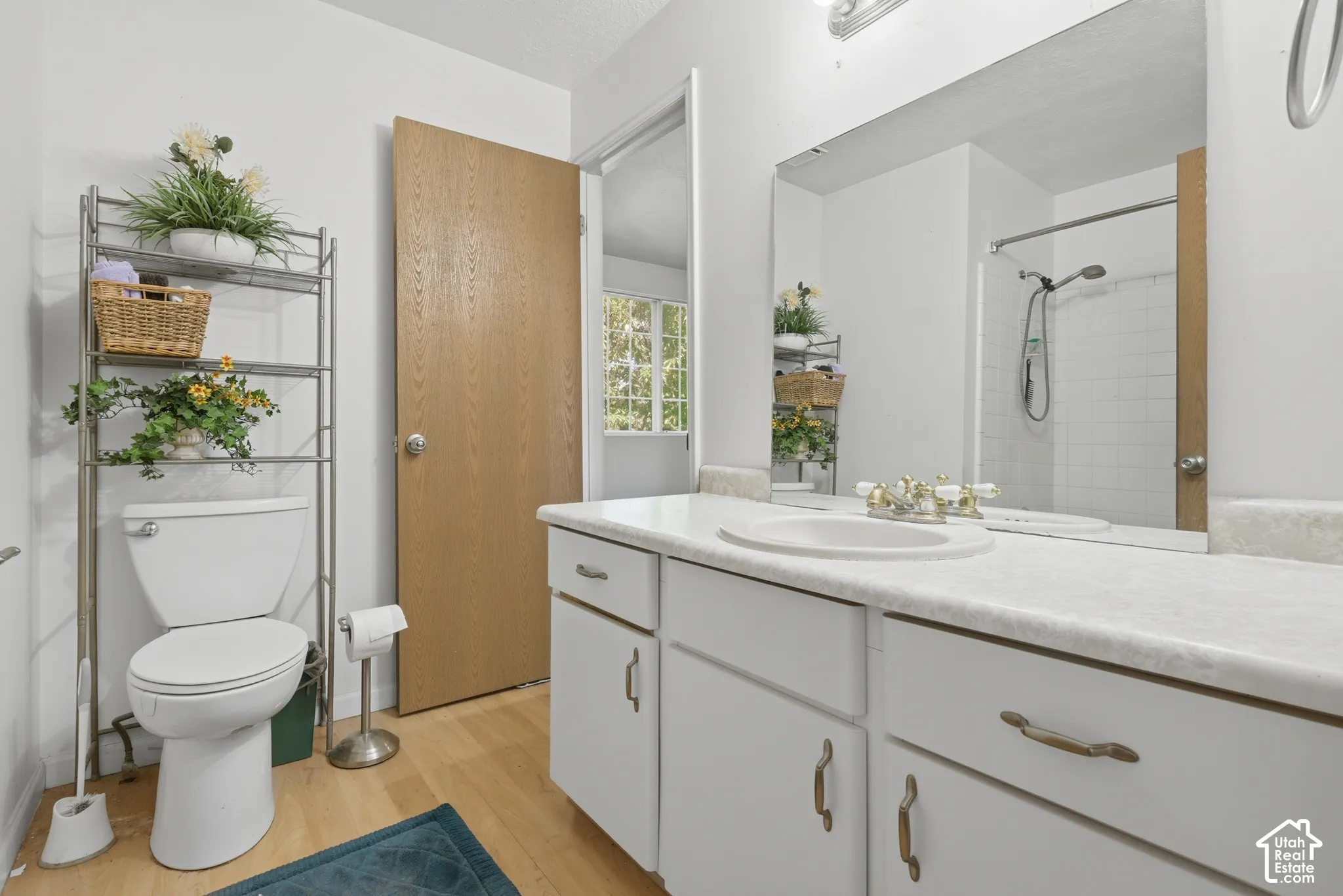 White vanity with ample counter space, integrated sink, and white cabinetry