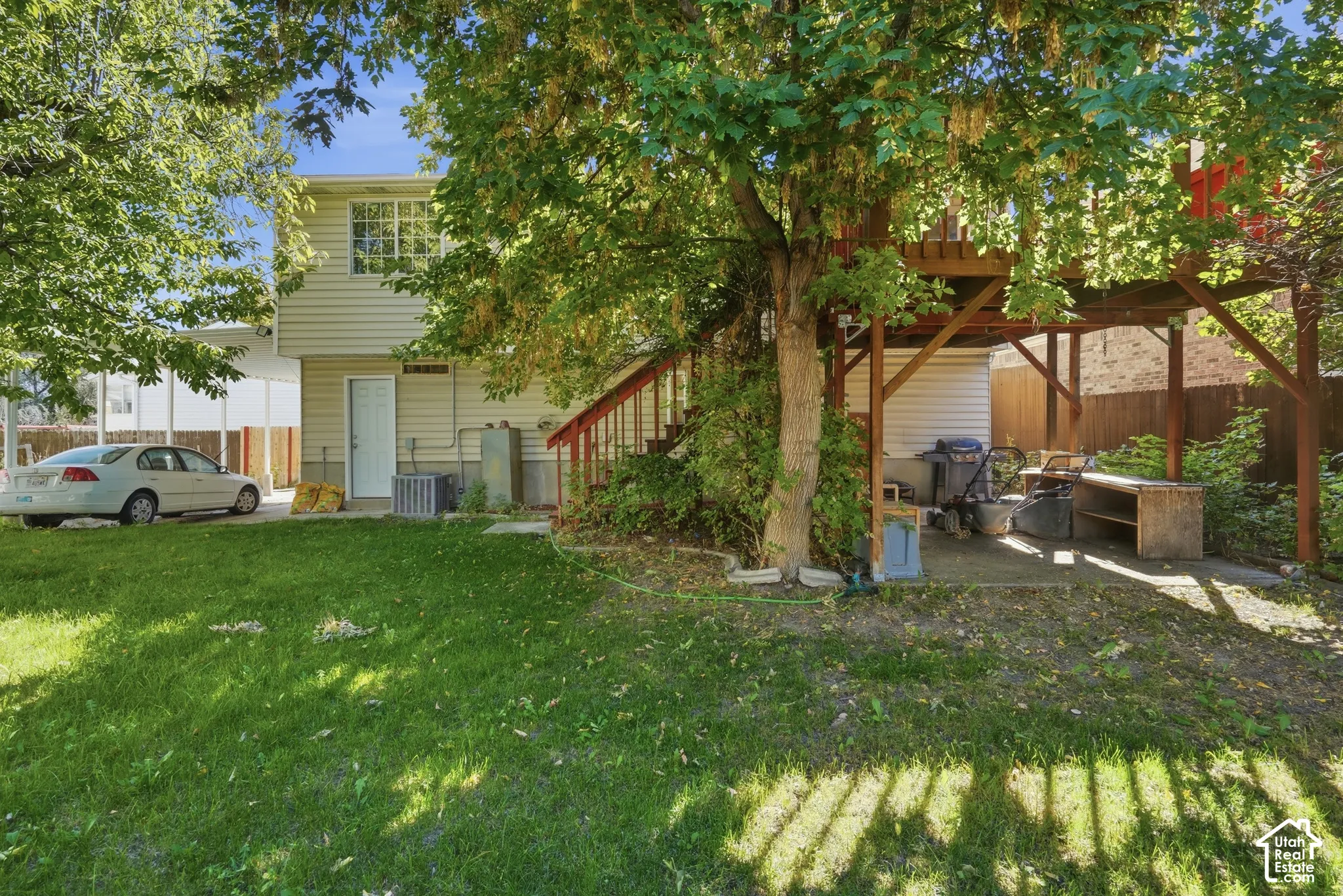 Expansive green lawn with mature trees and a multi-level deck featuring wood construction