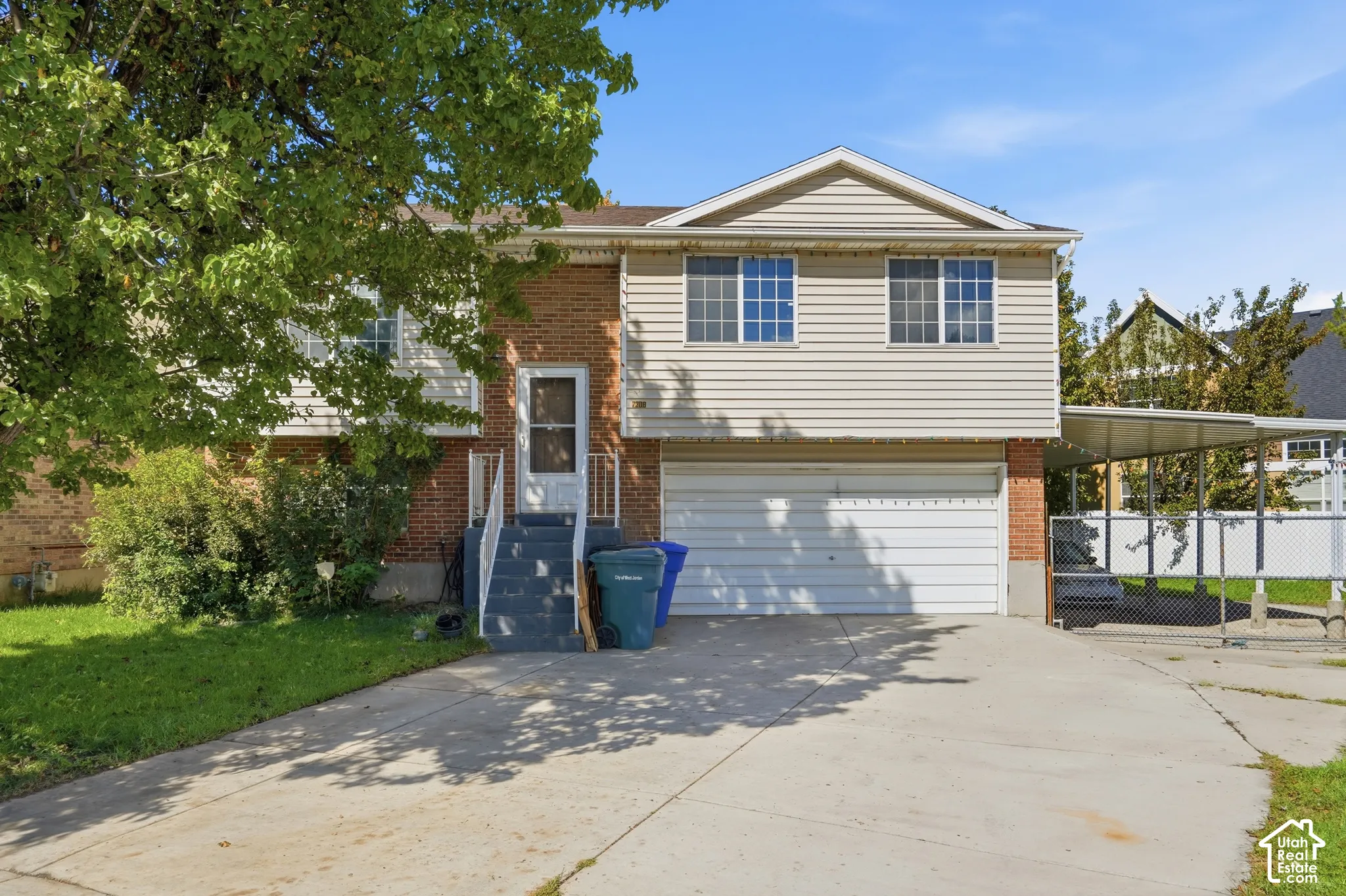 Brick and siding exterior with a pitched roof, attached two-car garage, and a covered carport