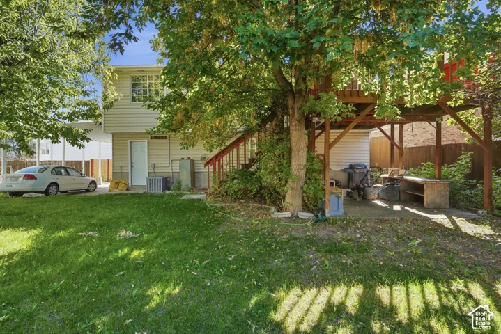 Expansive green lawn with mature trees and a multi-level deck featuring wood construction