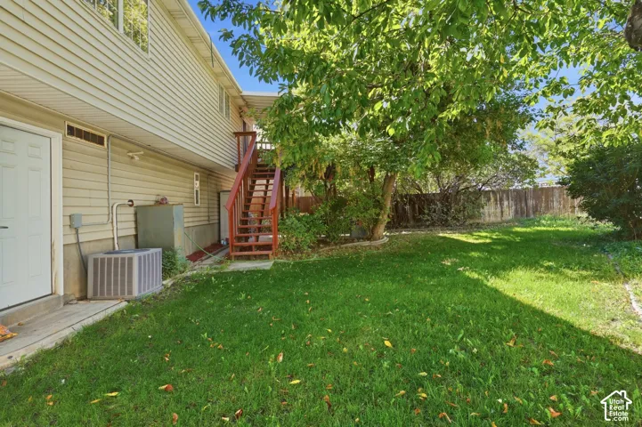 Expansive backyard featuring a green lawn, mature trees, and a wood privacy fence