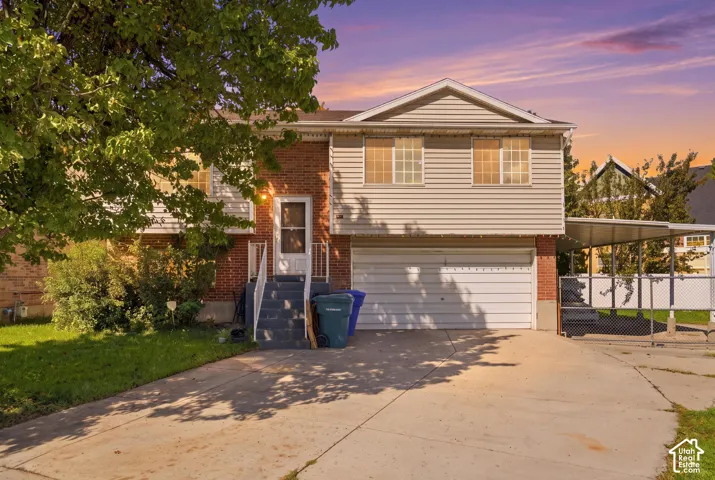 Brick and siding exterior with a two-car garage, upper-level windows, and a covered carport structure