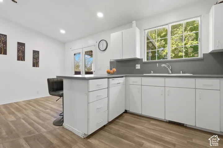 White cabinetry with brushed nickel hardware, gray countertops, recessed lighting, wood-finish flooring, and double glass-paneled doors