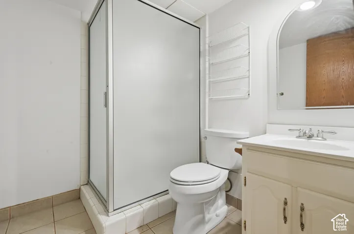 Frosted glass shower enclosure, white vanity cabinet with double-handle faucet, integrated sink, and an arched mirror