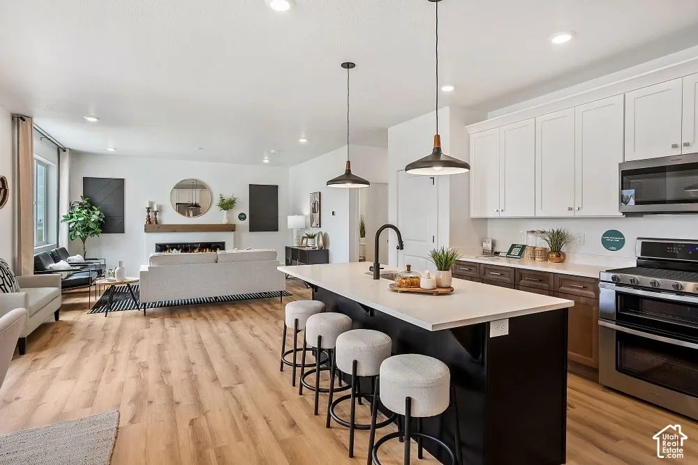 Open-concept living space with wood-finish flooring, a contemporary fireplace, and a kitchen island with seating