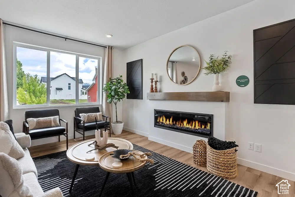 Expansive window providing ample light, wood-finish flooring, linear electric fireplace with wood mantel, and crisp white walls