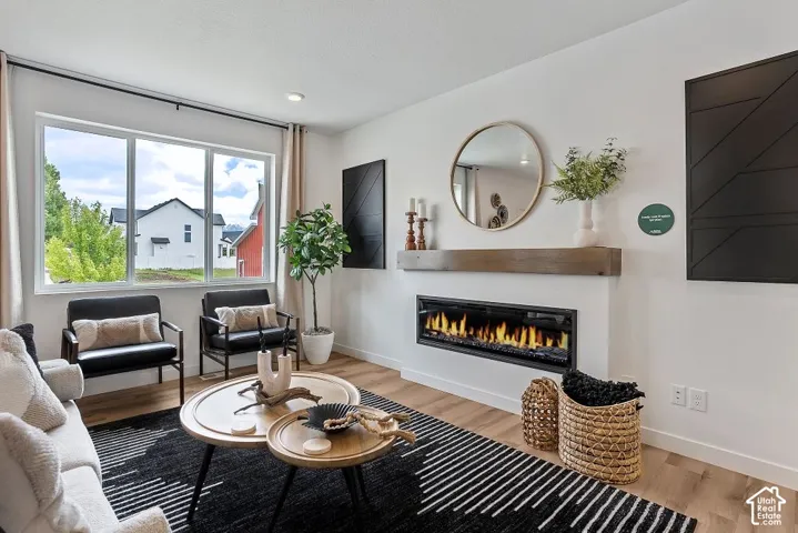 Expansive window providing ample light, wood-finish flooring, linear electric fireplace with wood mantel, and crisp white walls