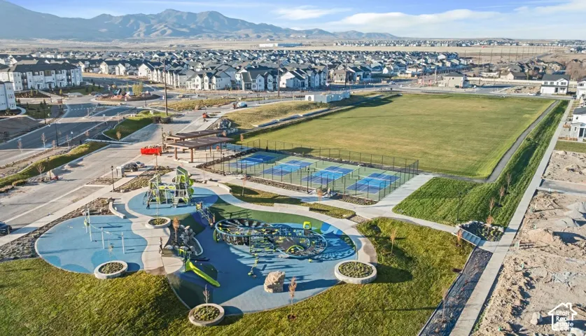 Expansive open space with a large grassy field, multiple pickleball courts, and a contemporary playground area