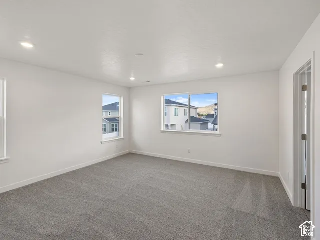 Recessed lighting, light gray carpeting, crisp white walls, and bright windows