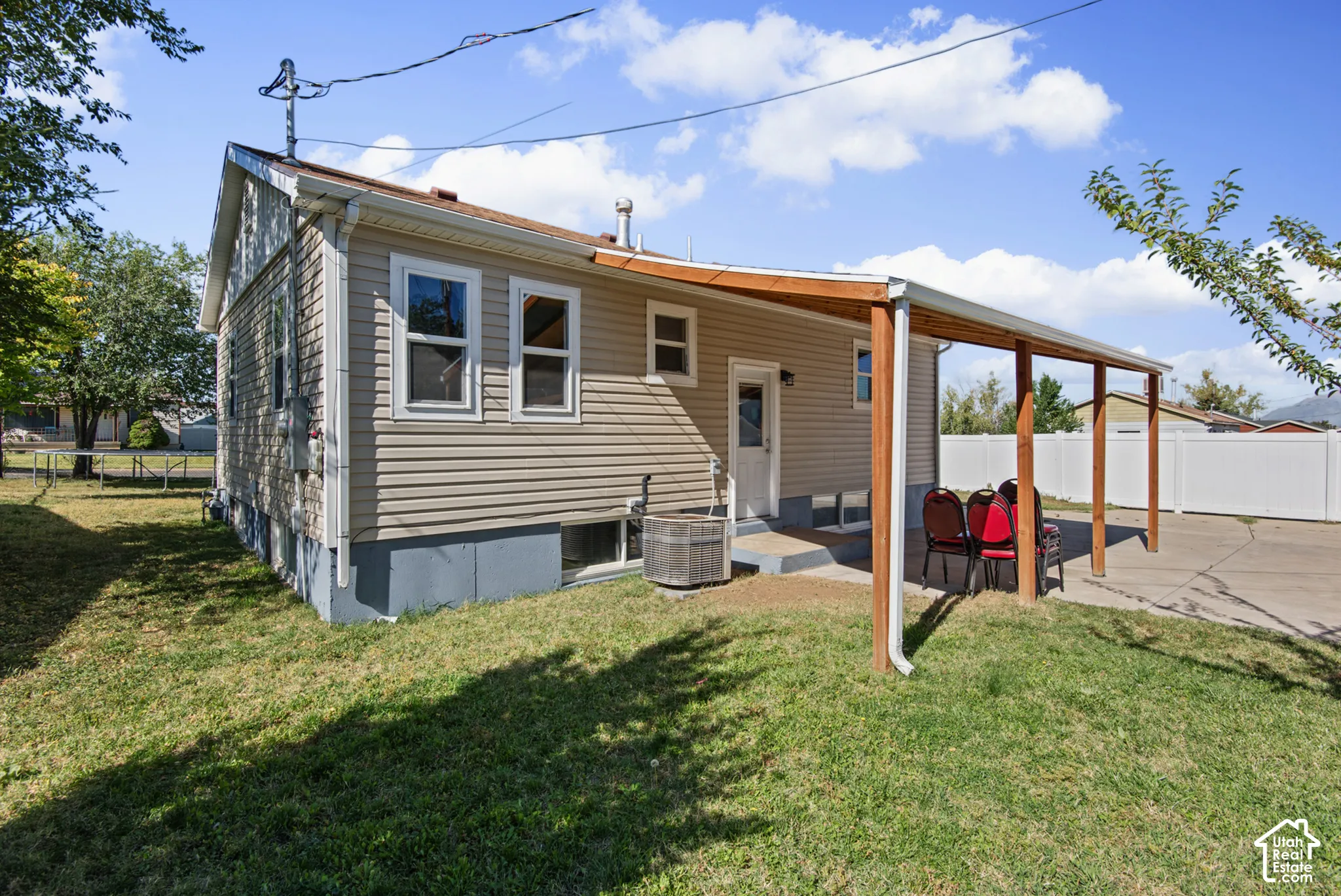 Side yard featuring a covered patio, concrete steps, and a white vinyl fence