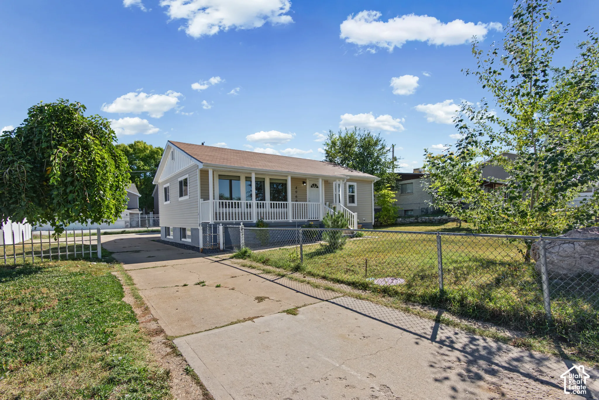 Siding exterior with a covered front porch, white railings, and a concrete driveway