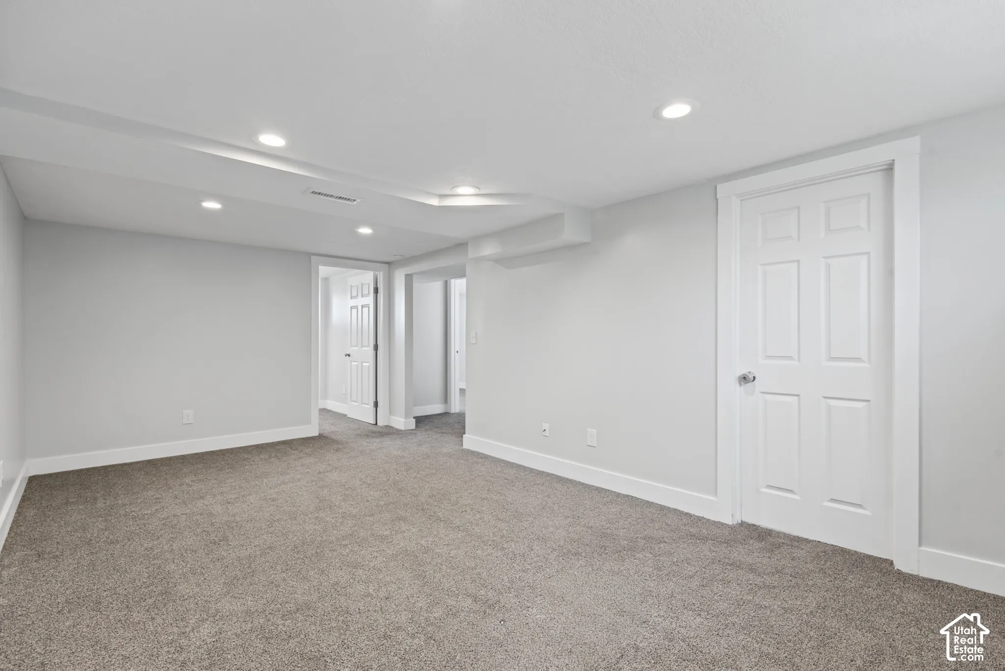 Recessed lighting, light gray walls, white trim, gray carpet, and white paneled doors