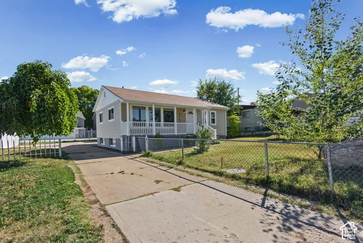 Siding exterior with a covered front porch, white railings, and a concrete driveway