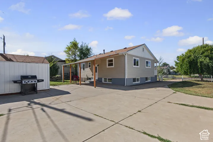 Spacious concrete patio with an attached covered patio, detached storage shed, and mature trees