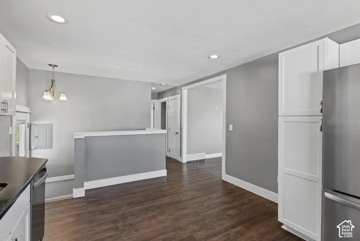 Wood-finish flooring, recessed lighting, and white shaker-style cabinetry with built-in pantry storage