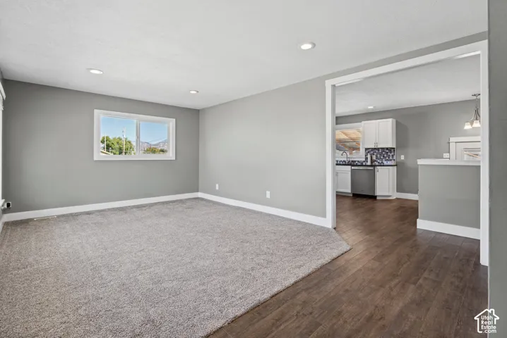 Recessed lighting, light gray wall color, light gray carpet, white trim throughout, and a window with a white frame