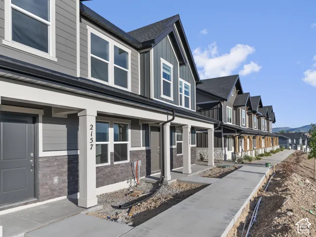 Contemporary townhome-style residences featuring dark gray siding and stone veneer accents