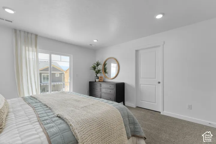 Sliding glass door leading to a balcony, recessed lighting, neutral carpeting, and a paneled interior door