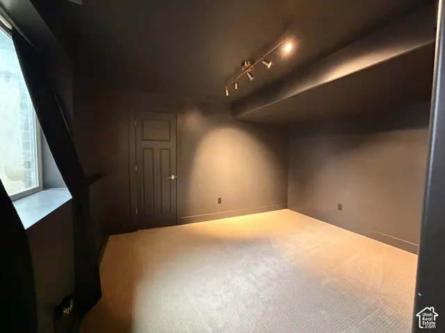 Recessed window, track lighting, neutral carpeting, and a built-in shelf