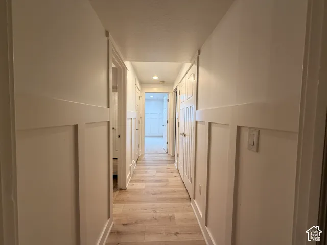 Hallway featuring wainscoting, wood-finish flooring, recessed lighting, and panel doors