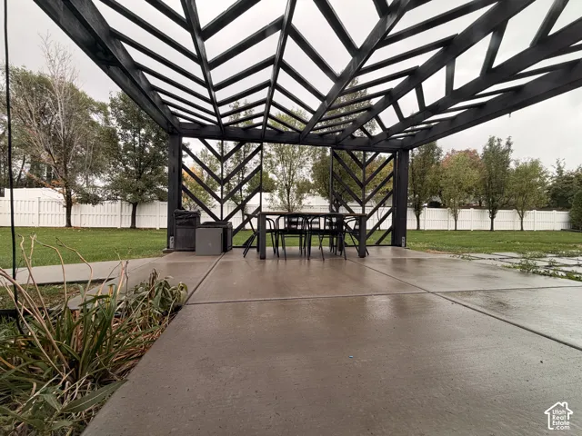 Modern pergola with geometric lattice design, expansive concrete patio, and a manicured lawn
