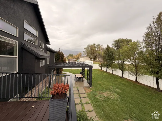 Dark exterior with multiple windows, wood-finish deck, and black metal railing