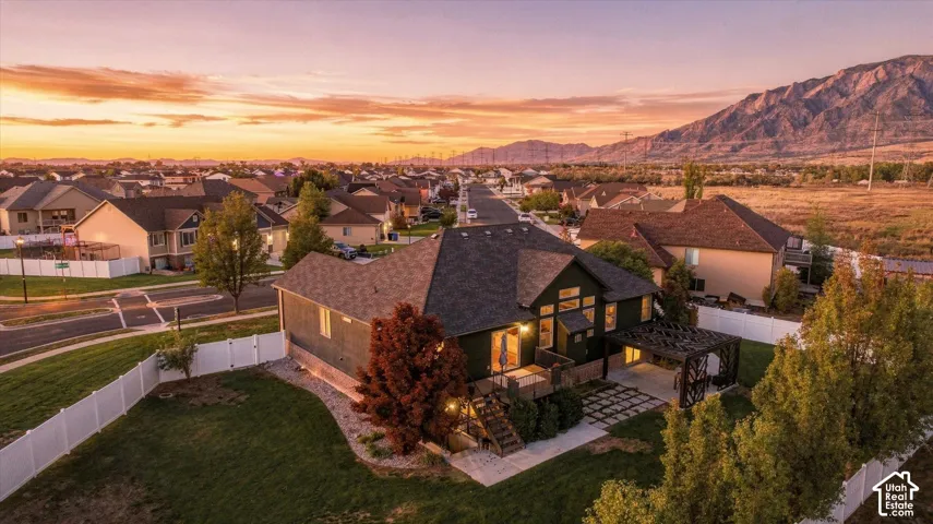 Aerial perspective featuring a multi-level deck, a pergola, a fenced backyard, and a mountain backdrop
