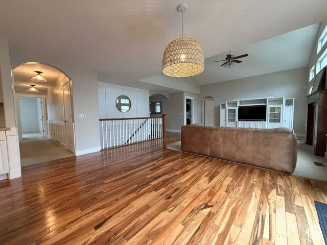 Hardwood flooring, vaulted ceilings, built-in entertainment center, and archway entry