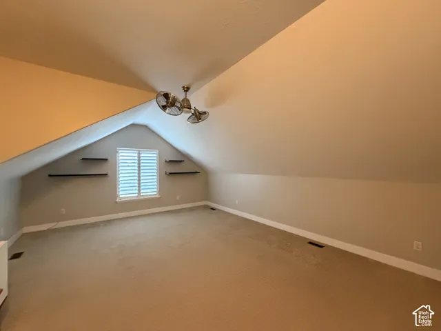 Vaulted ceiling with a ceiling fan, window with white louvered shutters, and built-in wall shelving