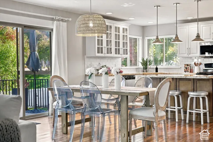 Kitchen featuring white upper cabinetry with glass-panel inserts, natural-finish lower cabinetry, stone countertops, a subway tile backsplash, and recessed lighting
