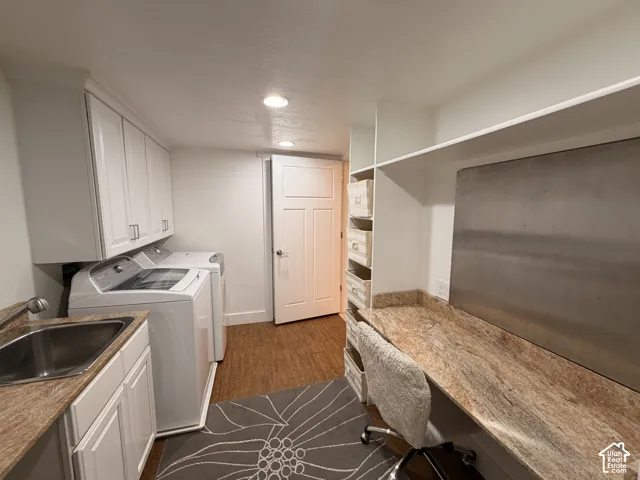 Laundry area featuring a stainless steel sink, white cabinetry with modern hardware, and stone-finish countertops