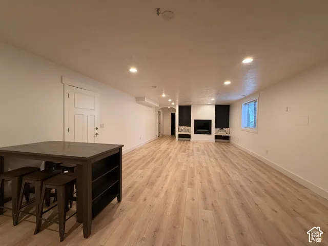 Expansive room featuring wood-finish flooring, recessed lighting, and a modern fireplace with built-in shelving