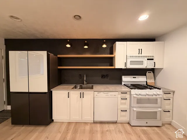 Full-size refrigerator, gas range with double ovens, integrated dishwasher, and stainless steel sink