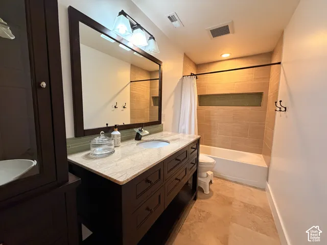 Vanity with a light-toned countertop, wood-finish cabinetry, and an undermount sink