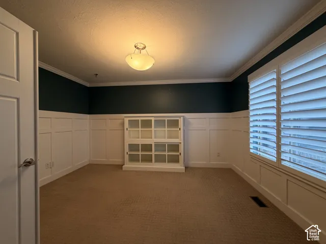 Board and batten accent wall, crown molding, white plantation shutters, and a semi-flush mount ceiling fixture