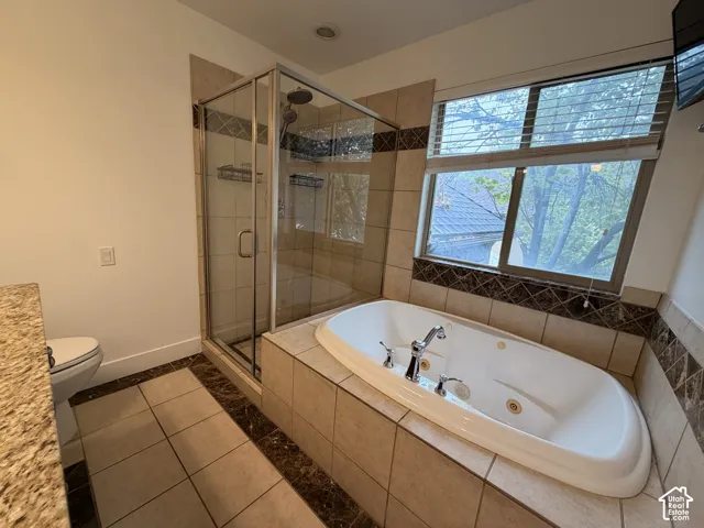 Primary bathroom's en suite. Tiled shower with glass enclosure, separate soaking tub, and granite-finish countertop