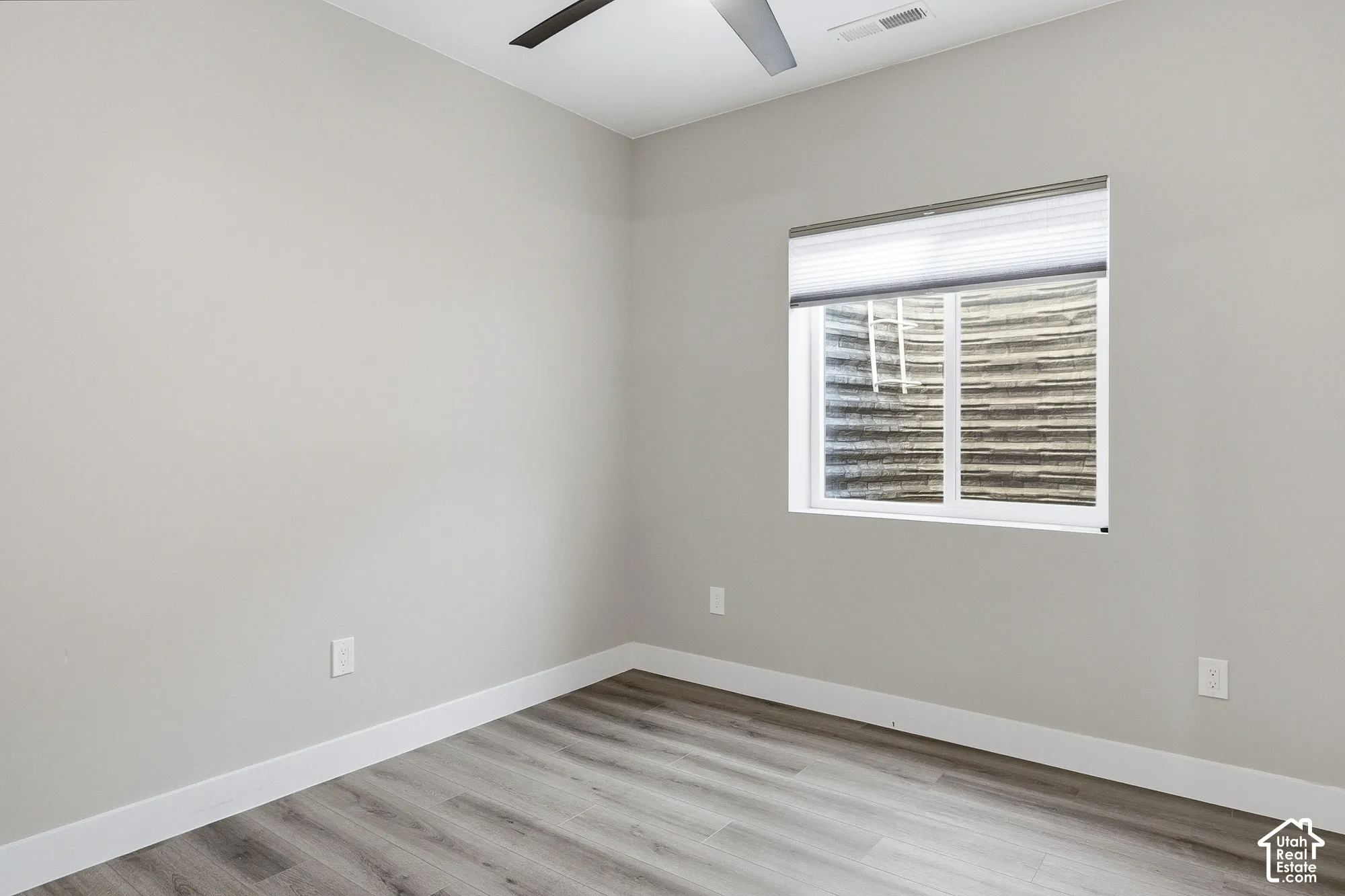 Neutral wall color, wood-finish flooring, white trim, ceiling fan, window with privacy blinds