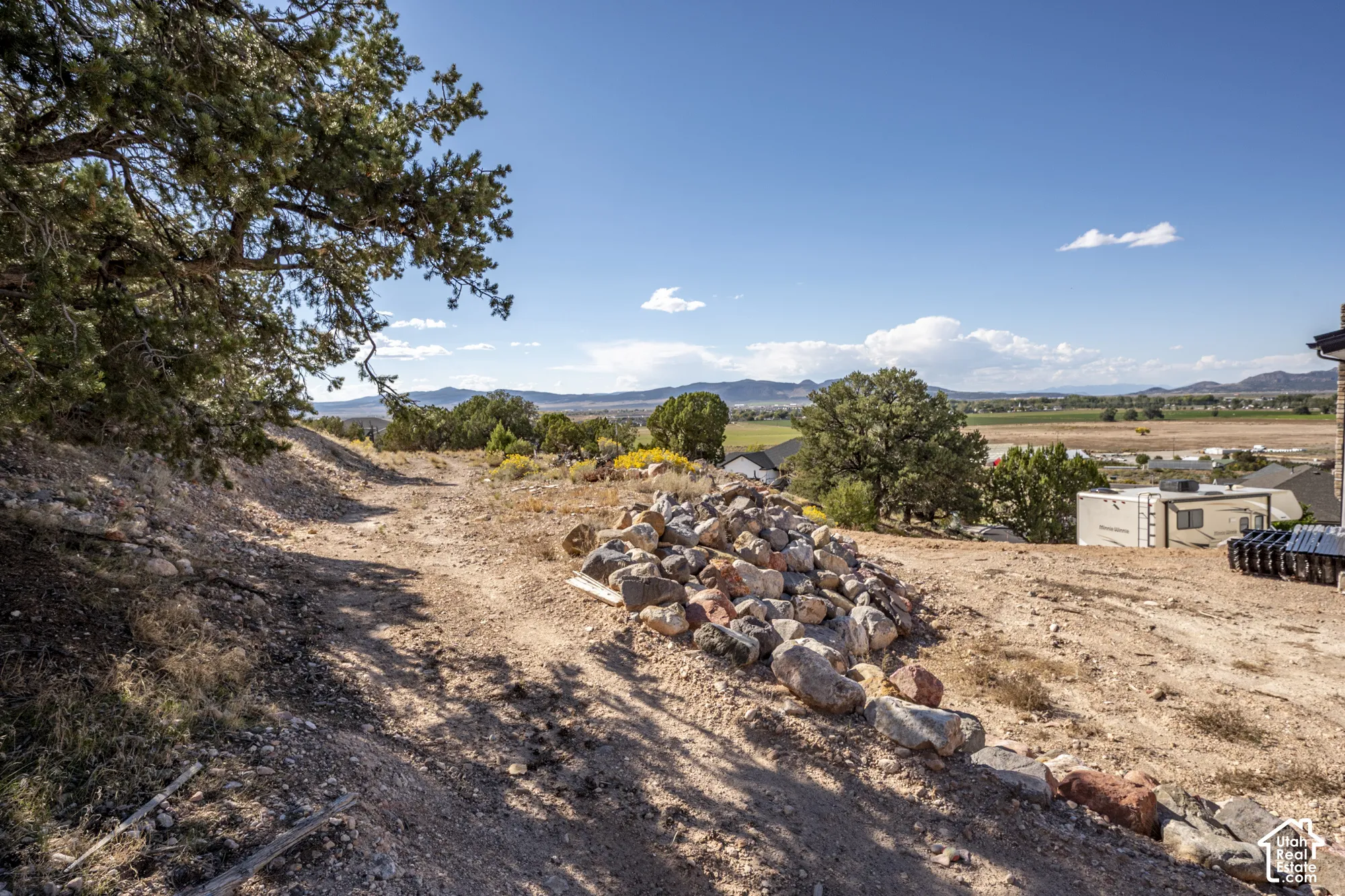 Expansive land parcel featuring natural terrain, mature trees, and a distant mountain range