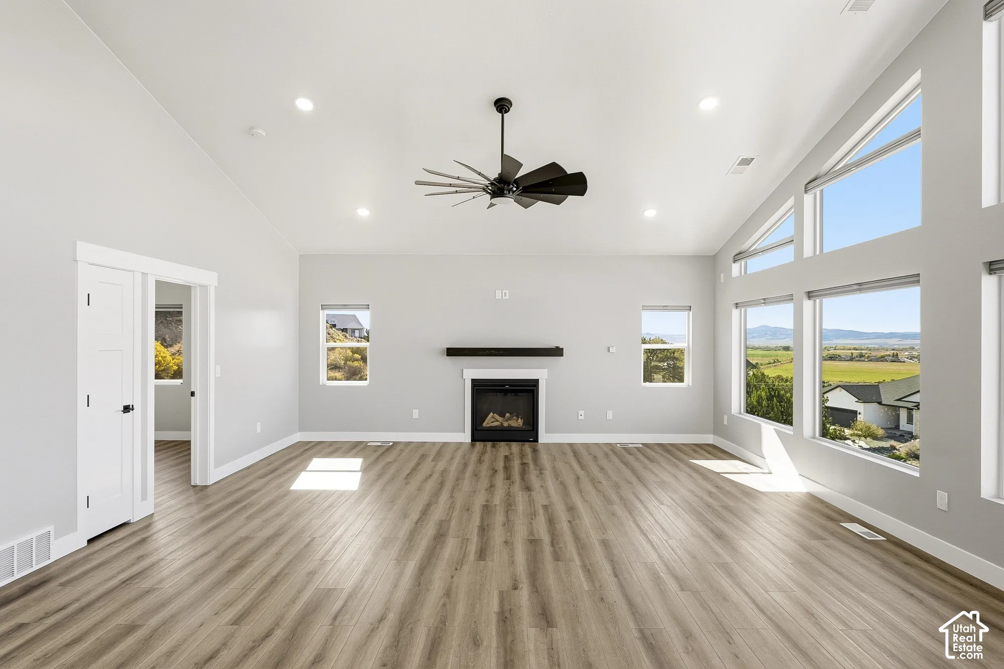 Vaulted ceiling with recessed lighting, wood-finish flooring, and a fireplace with a dark mantel