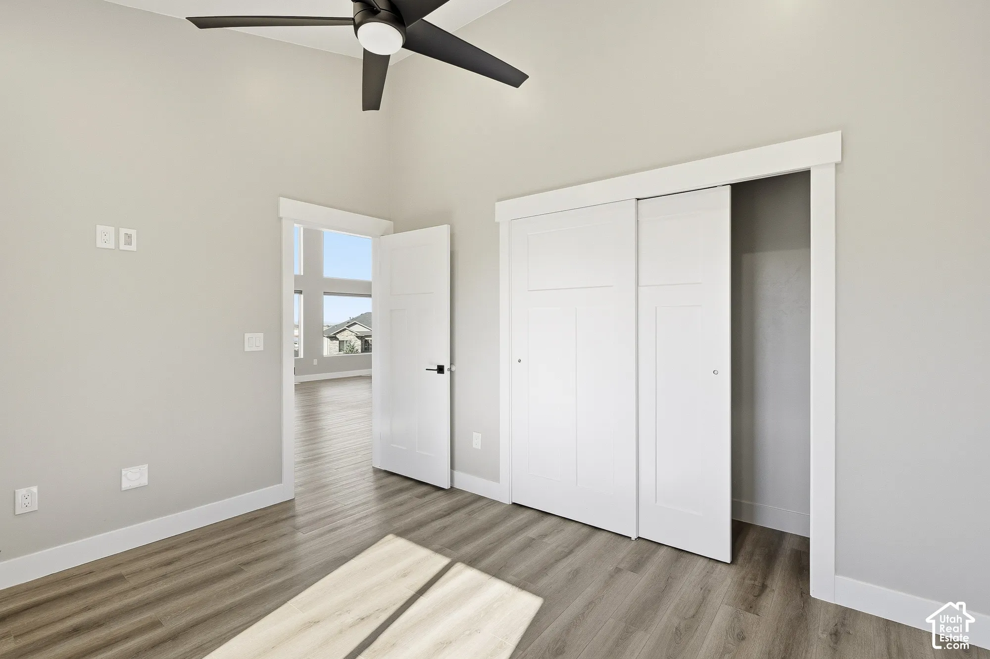Vaulted ceiling with a ceiling fan, wood-finish flooring, white sliding closet doors, and a solid core door
